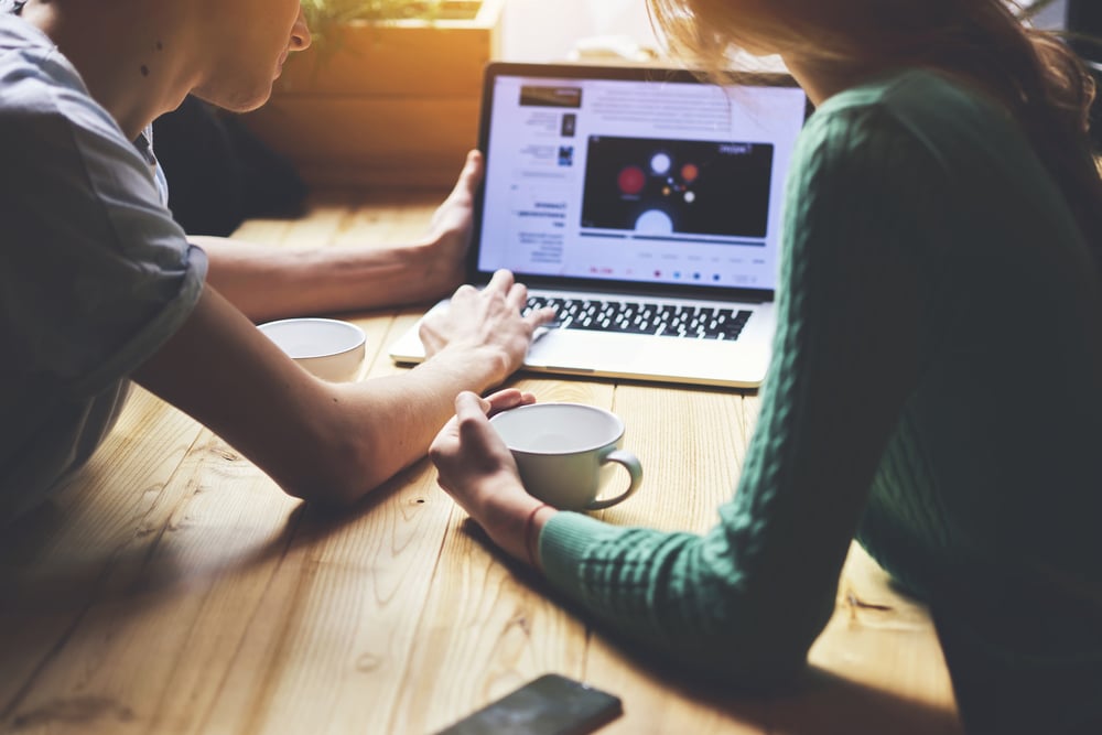 A couple watch a branded content video on a laptop. 